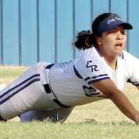 Harmoni Moore slides headfirst on the grass as she tries to catch a fly ball