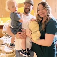 Daniel is holding Ross, while Callie is snuggling their new baby, Jett