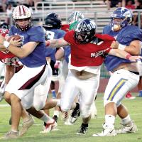 Ryan Sigler fights through a hold as he attempts to get to the East quarterback
