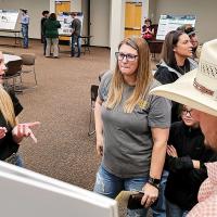 Kaysen Atkinson (left) talks with Susan Eisenhour (center) about a BlueSTEM research project done with partner Connor Stephens (cowboy hat)