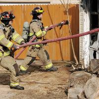 Tanner Hood, left, pulls slack on a water hose as Ty Gulickson moves into position