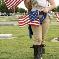 Madison Bigger helps place flags on the gravesite of a veteran