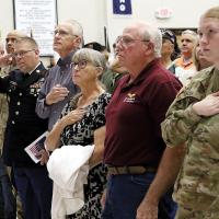 Veterans, students and guests stand for the national anthem