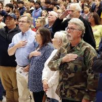 John Ferguson (in camouflage jacket) stands for the national anthem along with his wife