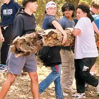 Members of EHS’ football team help move a broken tree trunk