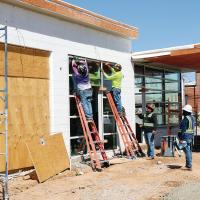 Construction workers install new glass into the front windows of the Filling Station