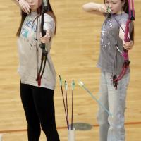 Nyley Miller (left) watches her light blue arrow fly toward the target as Rayne Bramlet takes sight on the target next to Miller
