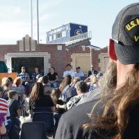 A man wearing a Vietnam War veteran’s cap listens to Brian Rukes talk