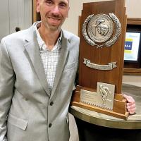 Ludy Griggs stands beside the NCAA Division II runner-up trophy