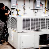 Gustavo Gonzalez installs a thermostat on a newly donated HVAC unit