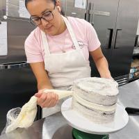 Allie Diaz putting icing on a custom cake order
