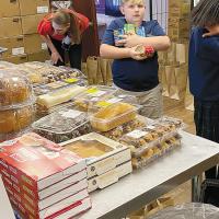 Mrs. Tilton works behind the scenes as Grant Peake delivers an armful of canned goods