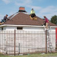 Workers nail down new shingles on the roof of the Darlington Jail