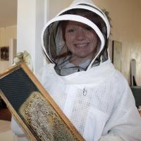 Brooklynn Mitchum shows a hive frame which is almost half full of honey