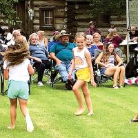 Children dance barefoot on the lawn at the Canadian County History Museum