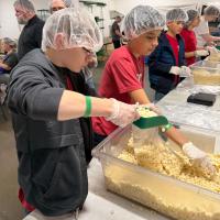 Gabe Scheirer and Kris Ortega work together to pack bags of potatoes