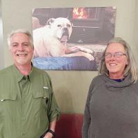 Mike and Janice Freeman stand in front of a photo of their dog Buddy