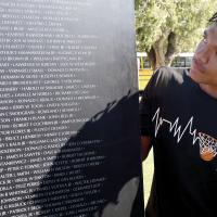 Kaleb Blackwolf looks over the names on one of the panels