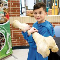 Landon Findley holds up a massive bone from an elephant