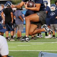 Lathen Pruitt hurdles a trash can used as a simulated defender