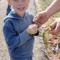 Rhiller Ellison smiles as he gets help holding up a small bass