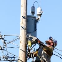 Nathan Grant checks out a fuse holder on top of a pole