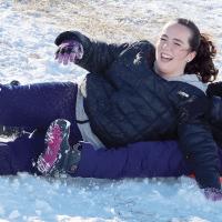 McKenzi Smith and Aspen Witherspoon laugh as they slide down the north side of Lake El Reno dam