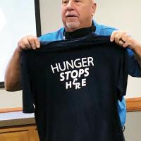 Craig McVay holds up a T-shirt with the slogan Hunger Stops Here