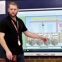Nick Phillips uses a smart board to ask students which category of instruments does a horn fall under