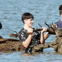 El Reno High School football players lift up a tree from the bottom of Lake El Reno
