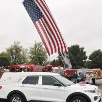 The hearse carrying Sgt. Thomas Duran’s body passes in front of a large American flag hoisted by the El Reno Fire Department