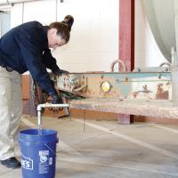 Stephanie Long fills a 5-gallon bucket of water