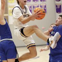 Hunter Mueggenborg jumps through two defenders on a drive to the basket