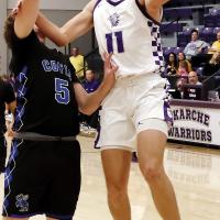 Jett Mueggenborg uses his arm to screen off a defender while shooting a fastbreak layup