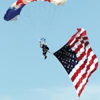 A member of Skydive Airtight glides with the American flag in tow