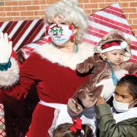 Mrs. Claus holds a young visitor dressed in a reindeer costume