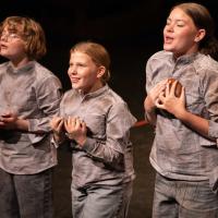 Abby Bass (center) sings “Food, Glorious Food”