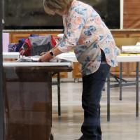 A precinct worker begins the closing process at a voting site