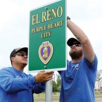 Jesse Trejo, left, and Eric Wilkerson install one of the new Purple Heart City signs 