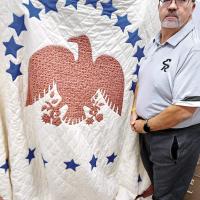 Glen Miller poses with the patriotic quilt that is being auctioned