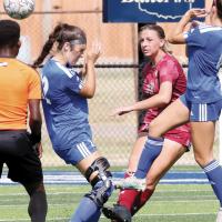 Miya Ingram kicks the ball down the field between two defenders