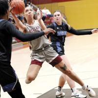 Ashlyn Evans-Thompson eyes the basket while jumping between two defenders