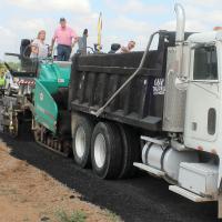 Jack Stewart and Tracey Rider watch as paving crews place an asphalt overlay