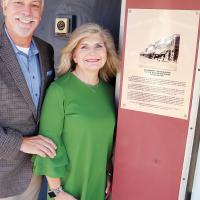 Roger and Anna Rinehart stand next to the plaque outlining the history of the downtown property the longtime El Reno couple own