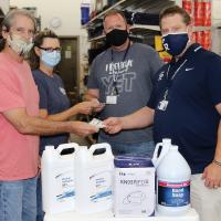 Tom Ross and Teresa Bates each hand over a KN-95 mask