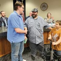 David Arndt and his son, Kaydayn present a gift to Ryder Watts, thanking him for his heroic actions