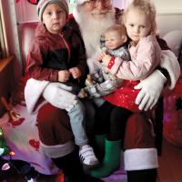 Santa Claus poses for a photo with young trolley riders