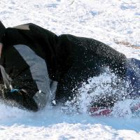 Kyston Overton tries to hang on to his sled while sliding sideways down a hill