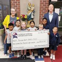 Shannon Statton and Owen Canfield pose with some students at Sacred Heart Catholic School