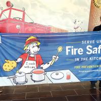 Layne Conaway holds up a fire safety banner with ER Fire Chief Jason Duff